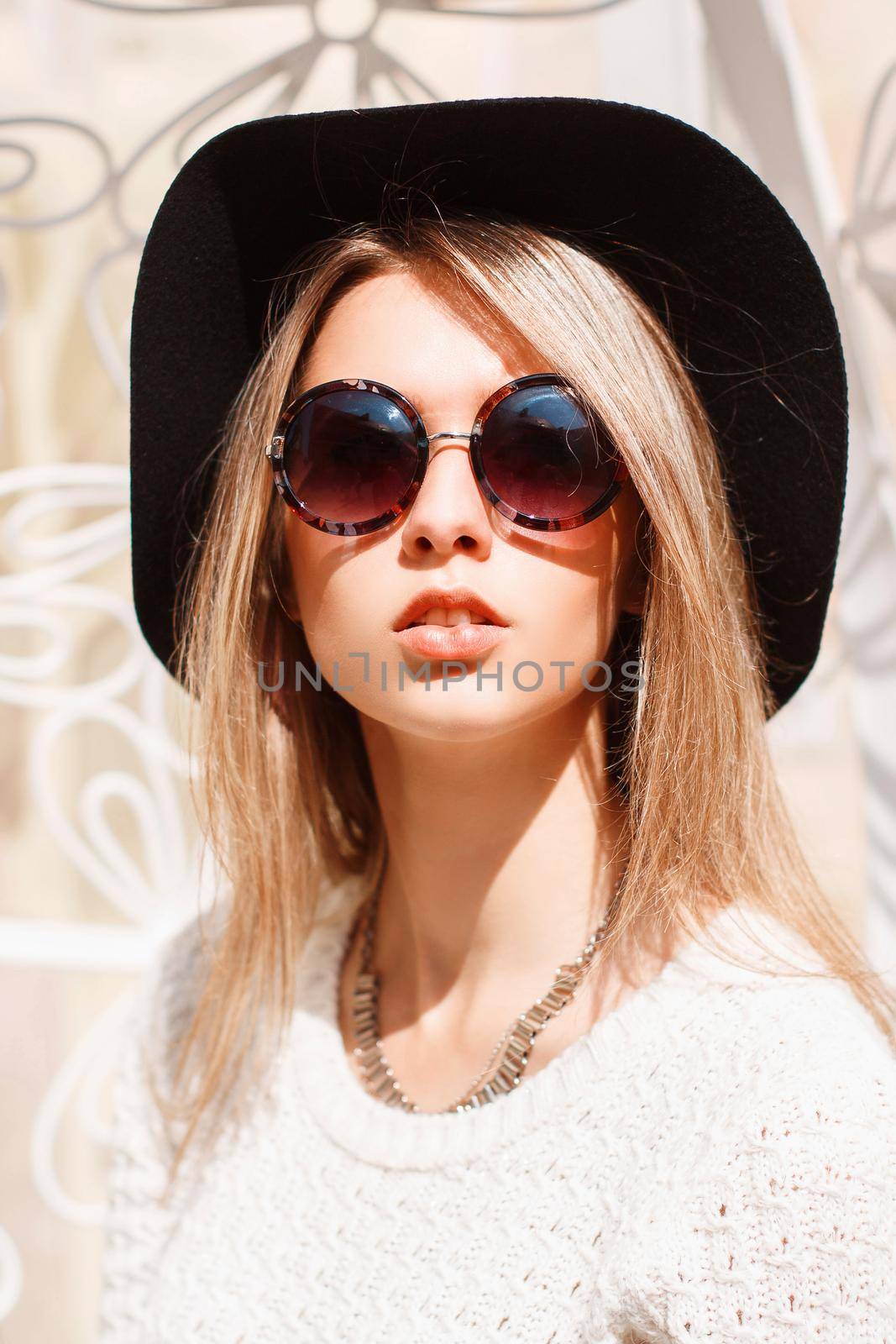 Portrait of a beautiful young girl in a black hat and round sunglasses on a sunny day. by alones