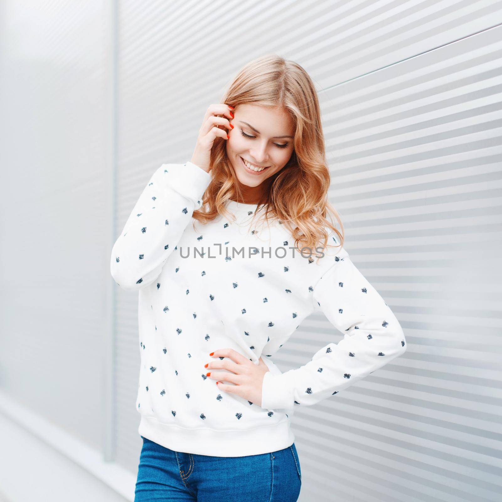 Portrait of a pretty smiling woman posing in front of modern metallic wall background