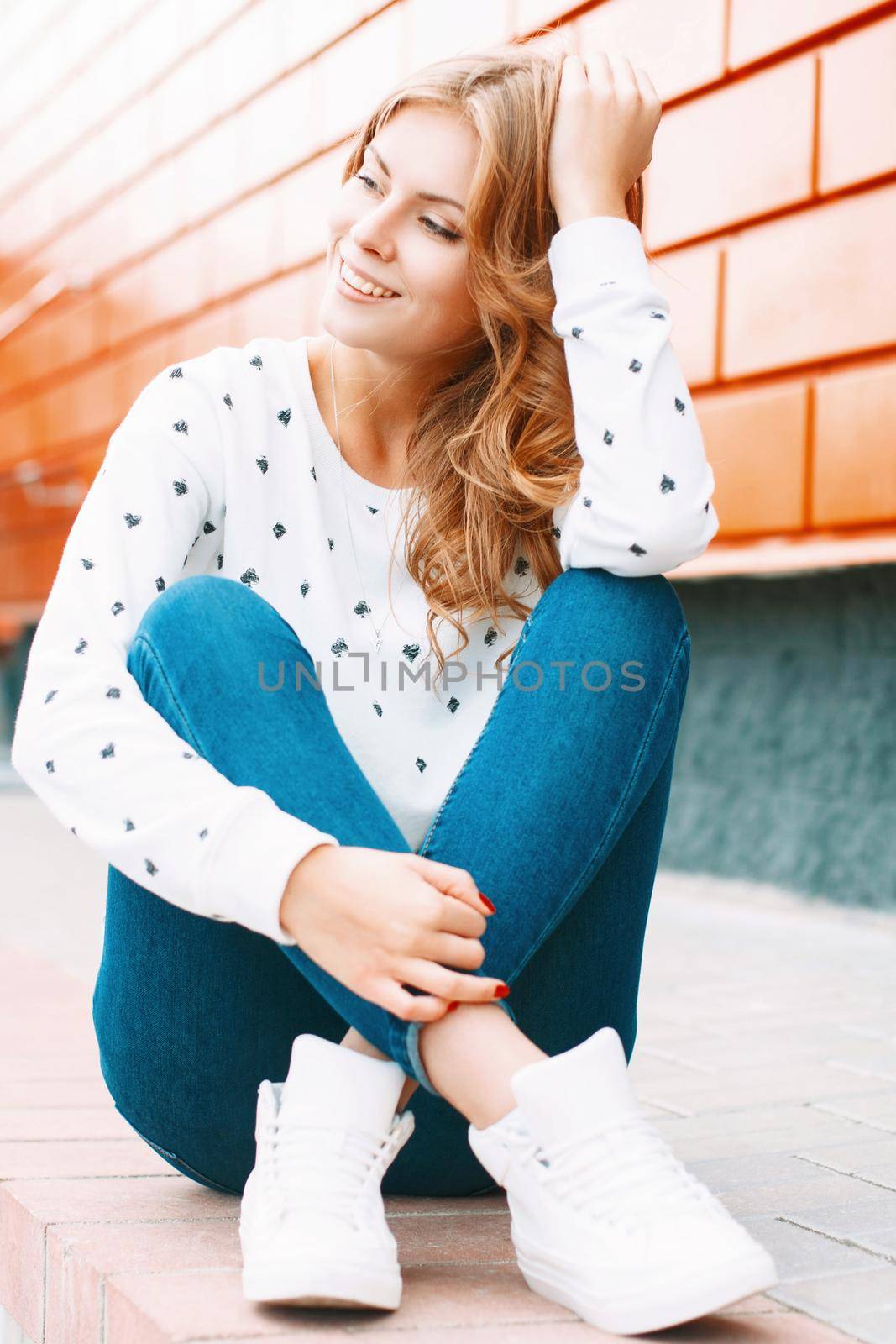 Beautiful stylish girl sitting near the colorful wall
