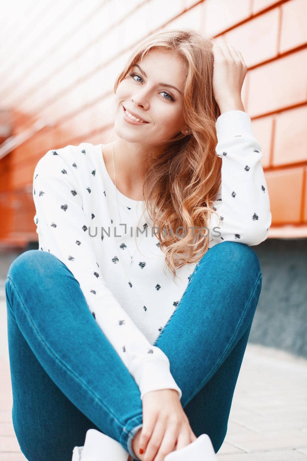 Beautiful portrait of a pretty smiling girl near stylish orange metal wall. by alones