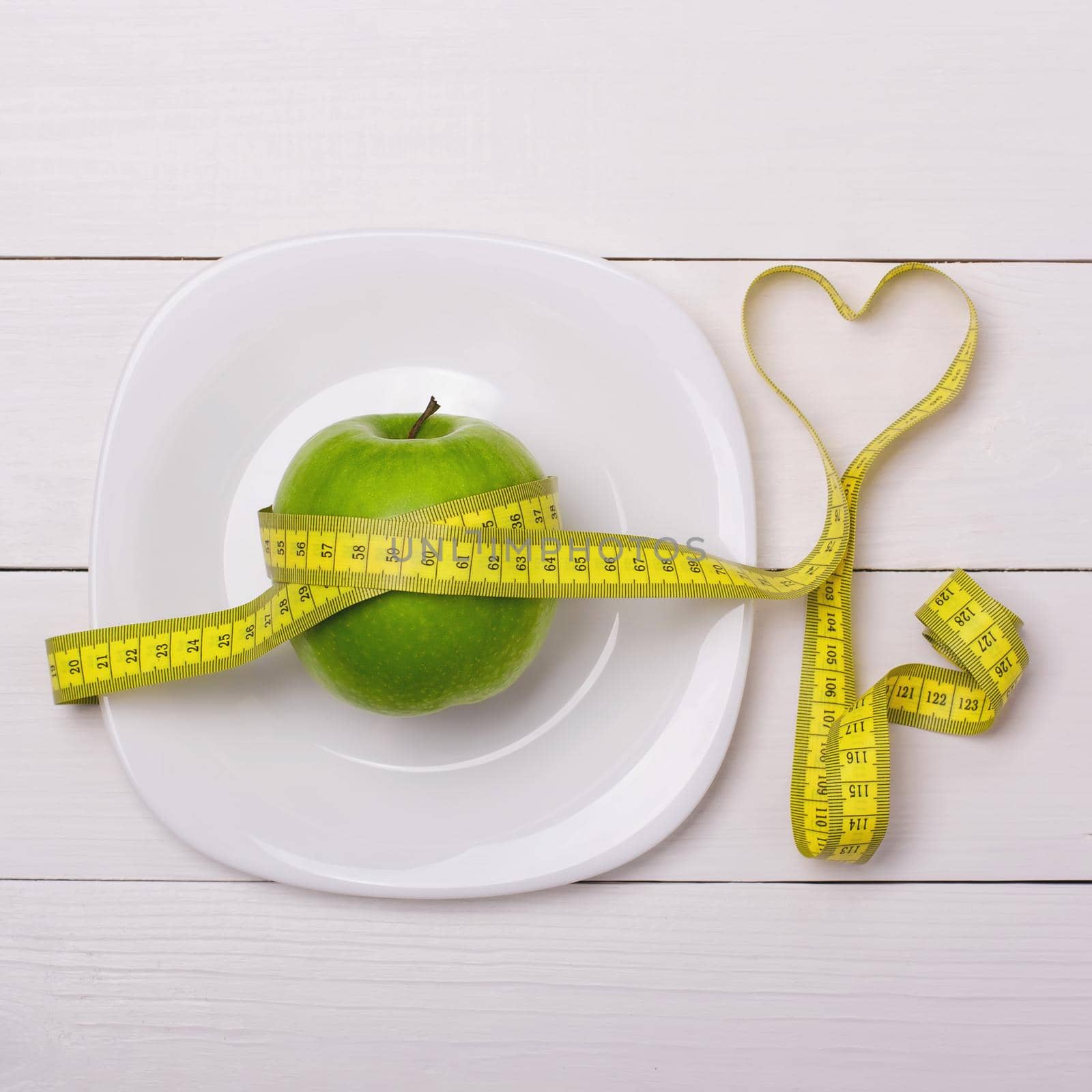 Apple and centimeter on the plate. Fitness healthy eating by alones
