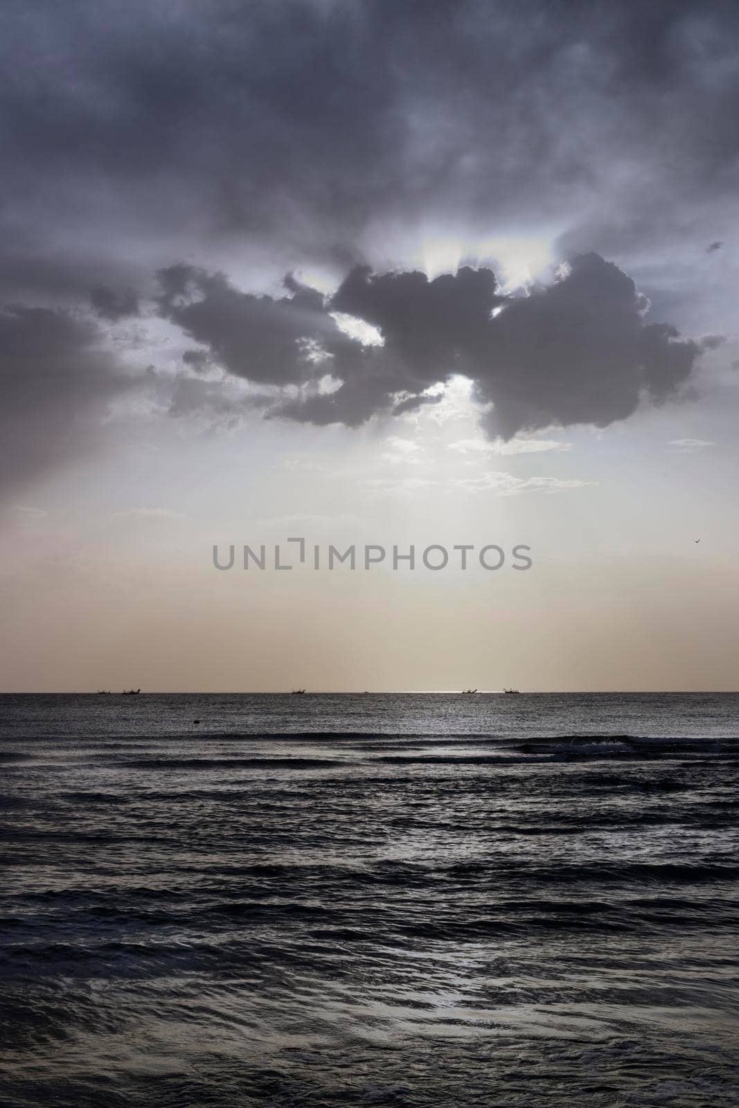 Beautiful sunrise on the sea , rays of sun behind the clouds ,on the horizon fishing boats