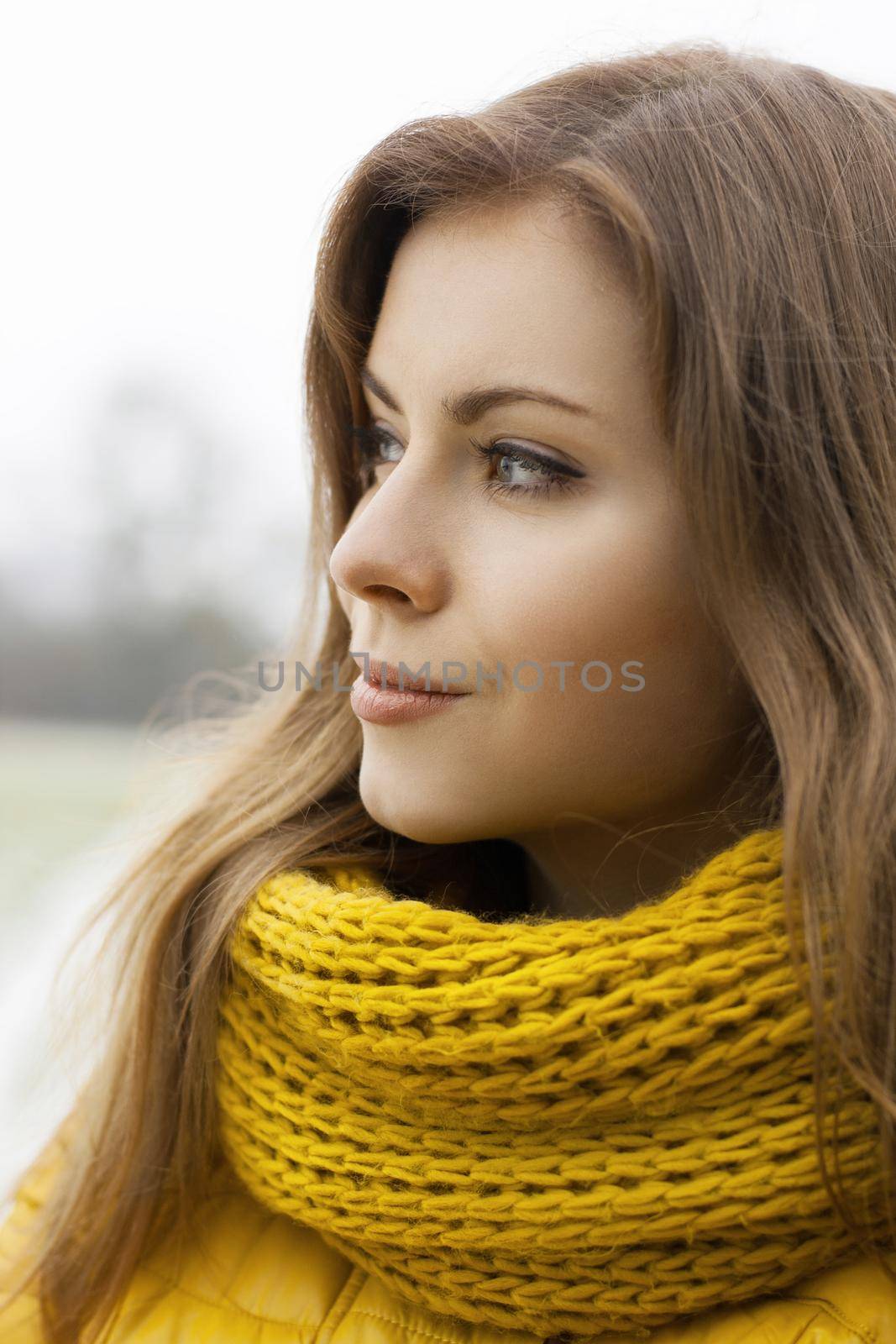 Pretty woman in a yellow knit scarf looks into the distance. Outdoor portrait. by alones