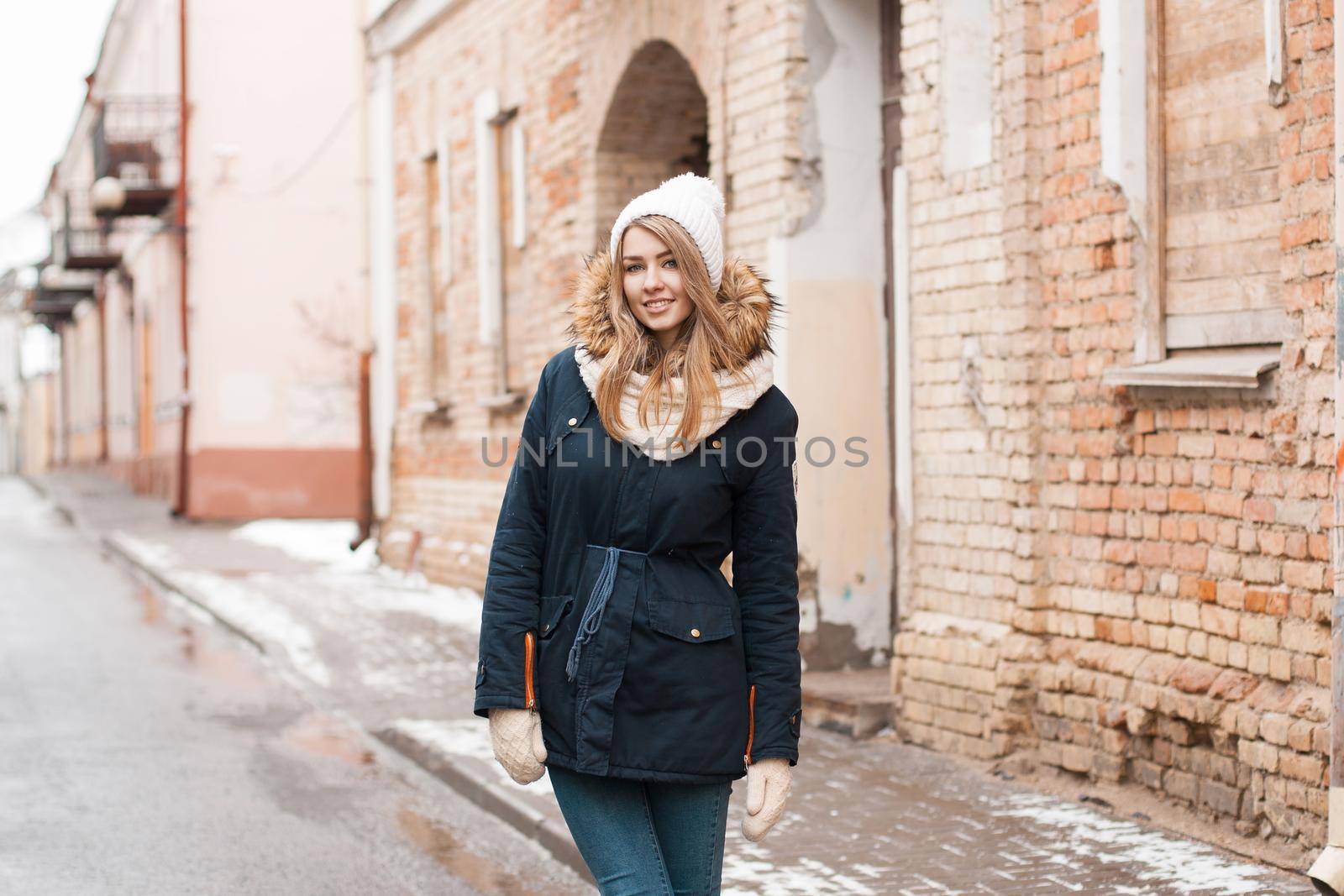 Beautiful woman standing near old brick wall. Old residential homes in the city center. Outdoors in winter. by alones