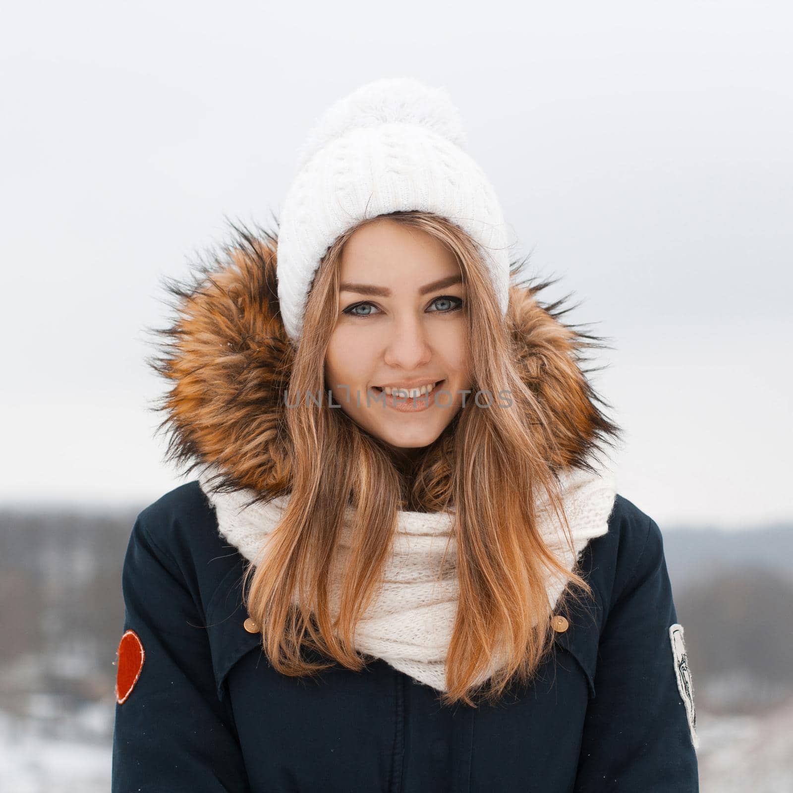 Sweet girl in a knitted hat and jacket smiles.Outdoors in winter by alones