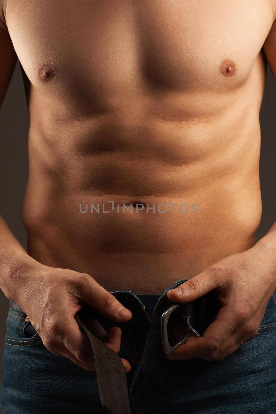 Man unbuckling the belt. Abdominal muscles and chest. Athlete. 
