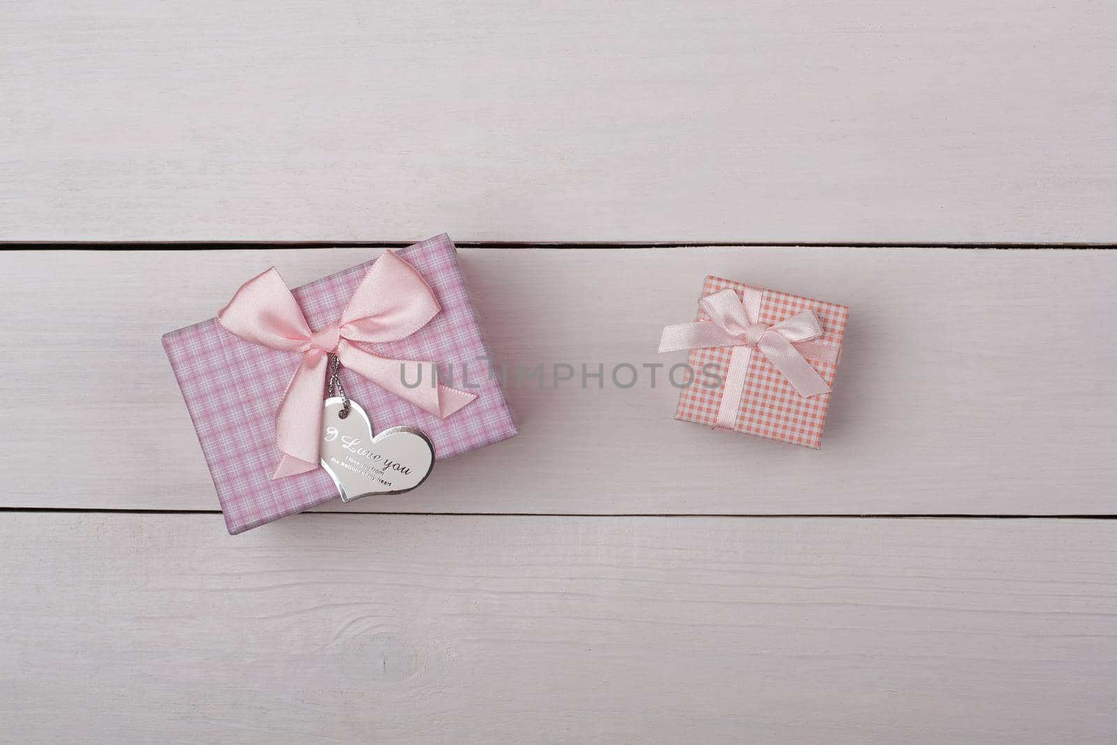 Two pink gifts with bows on white wooden table. by alones