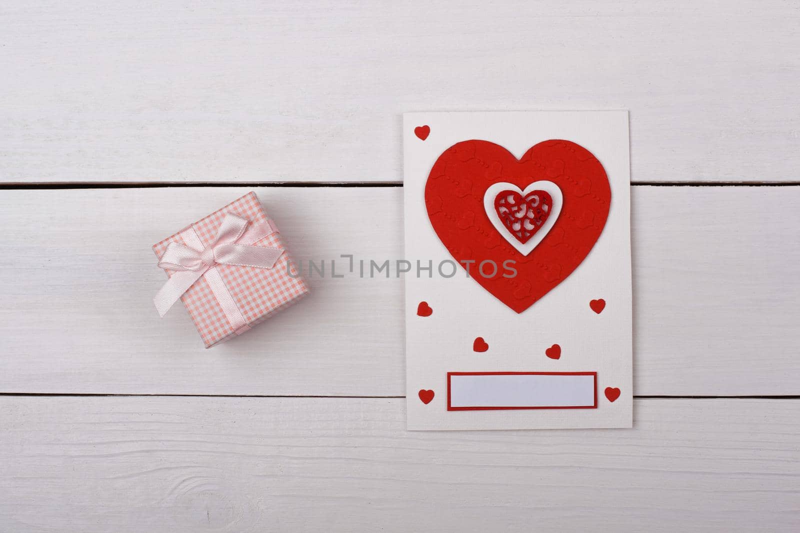 A gift and a card with red hearts on the table.