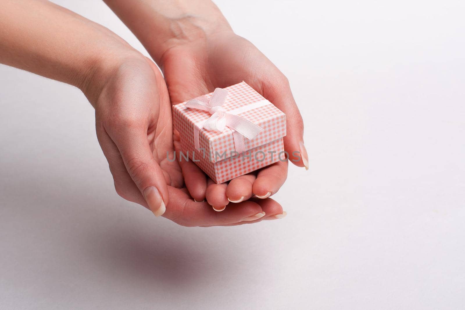 Female hand holding a gift with a bow.