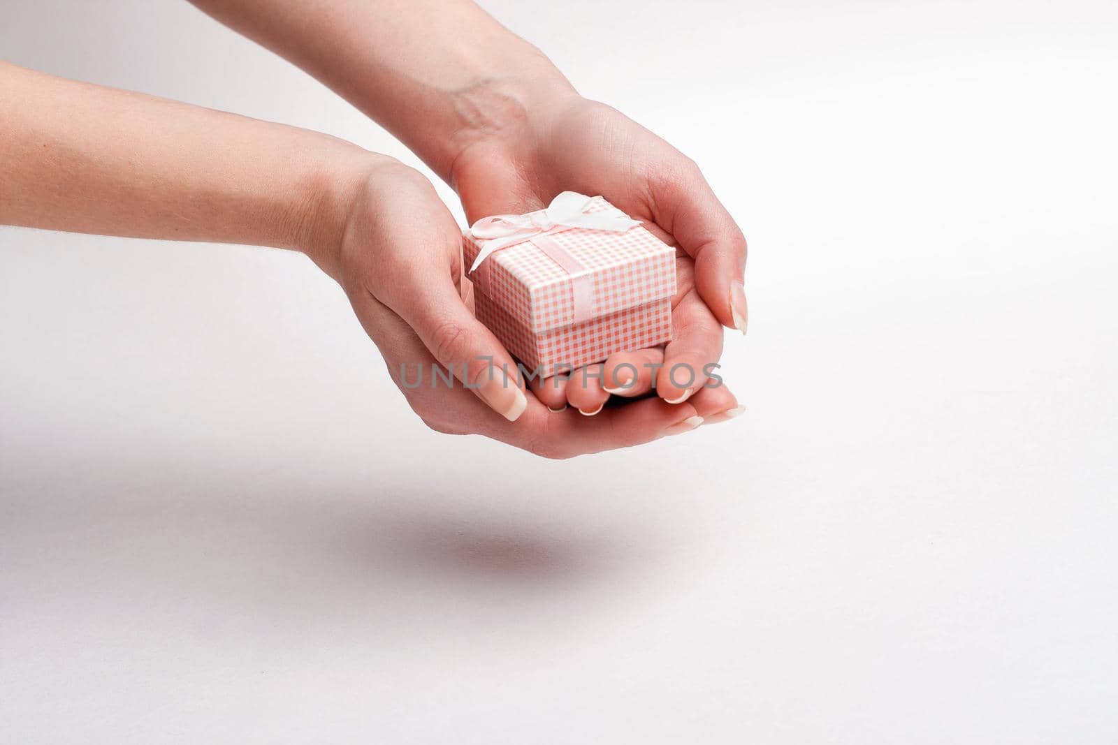 Female hand holding a gift with a bow.