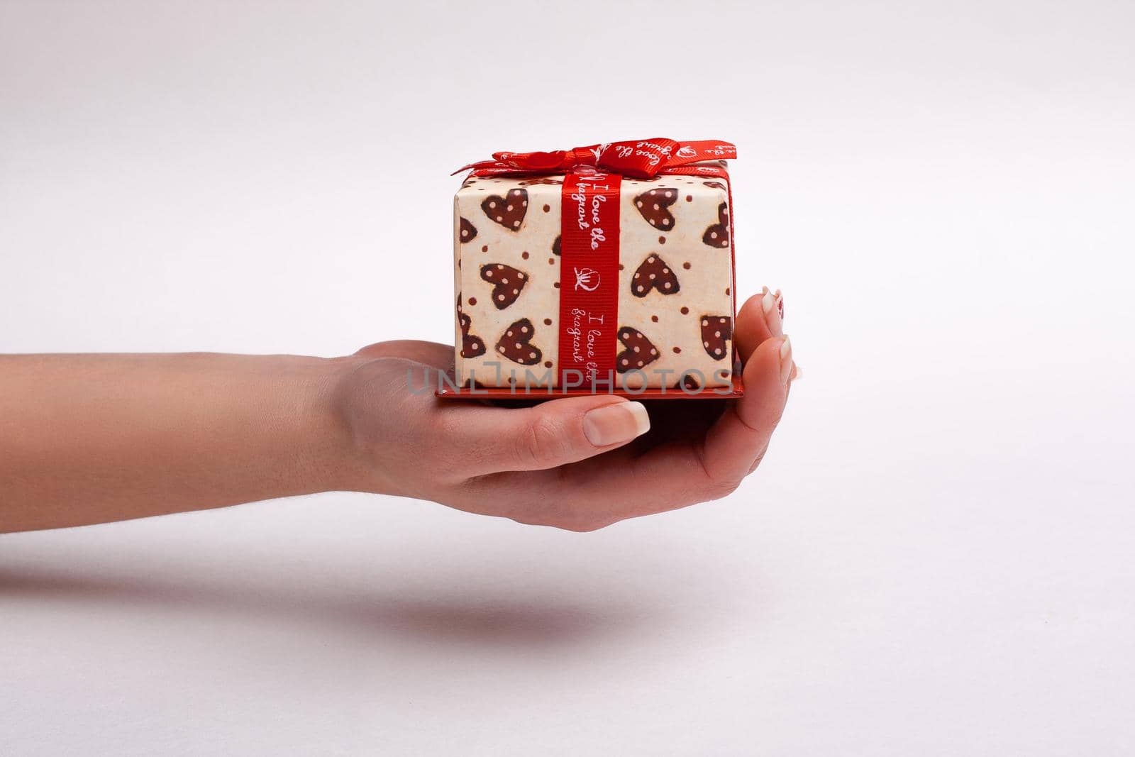 Woman's hand gives a beautiful gift box with a bow.