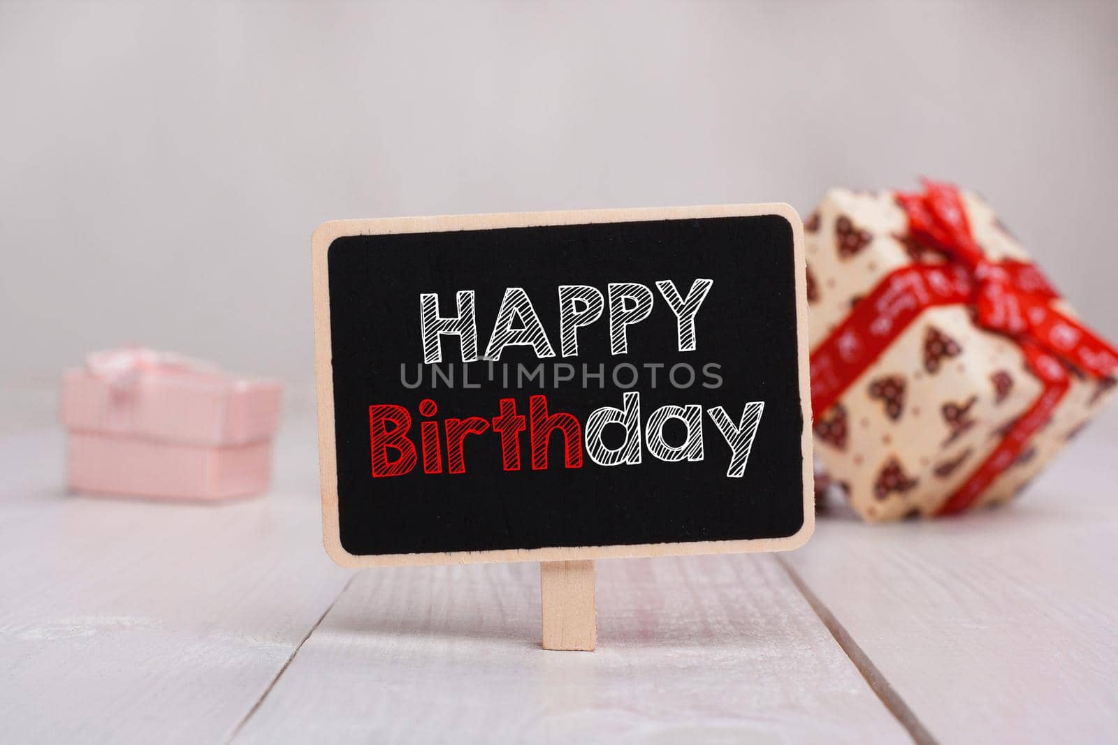 Black chalkboard with the Happy Birthday text on the table on the background with gifts.