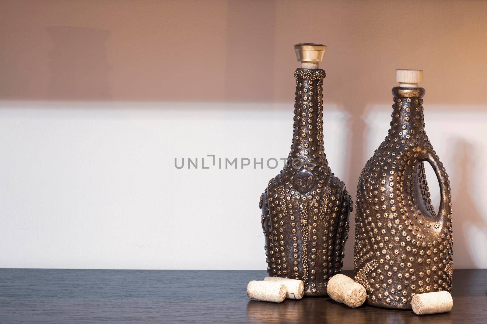 There are beautifully decorated wine bottles on the table and several corks lying nearby. by Sonluna