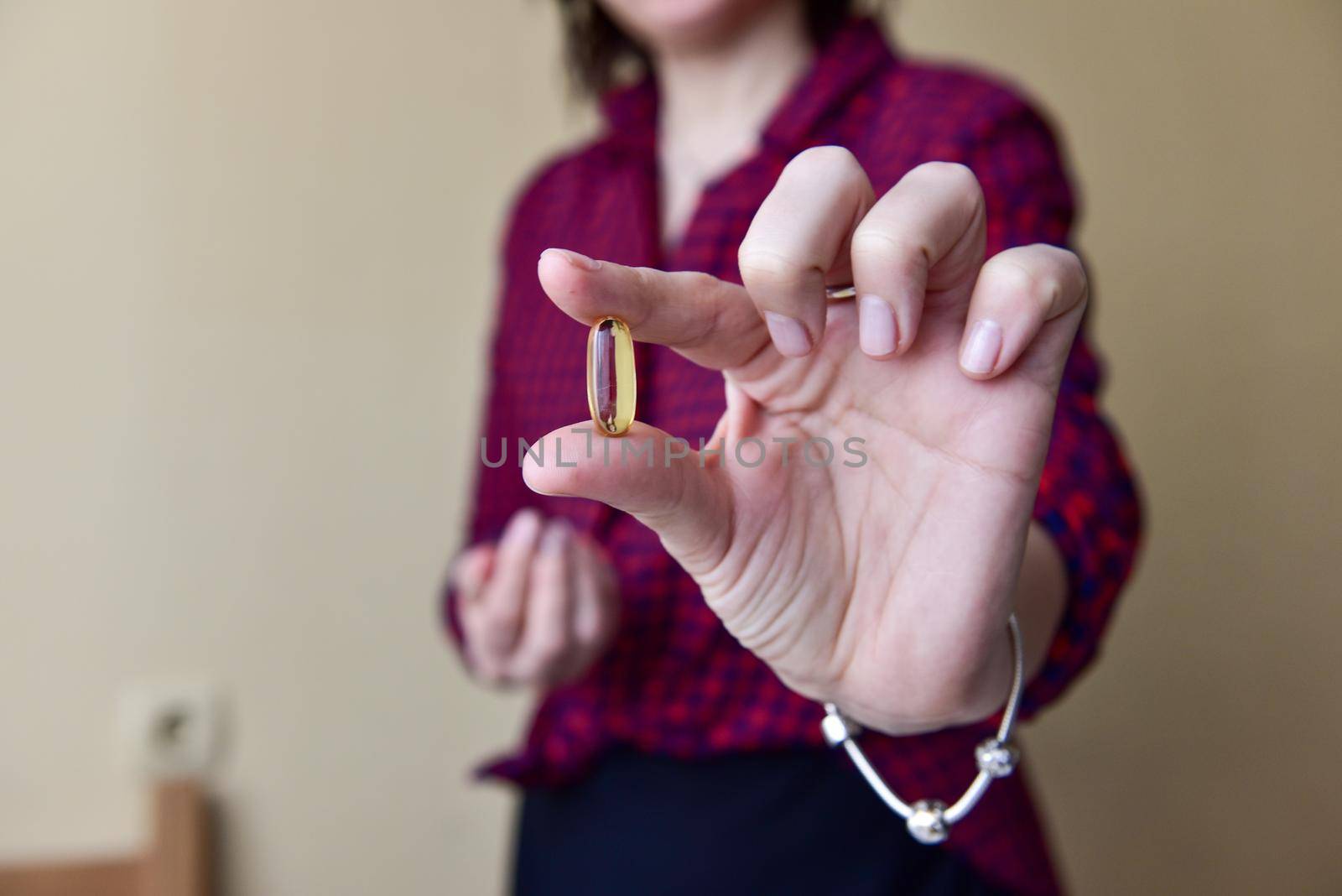 The woman in her hand holds a capsule of omega-3 fish oil. Medical healthcare, healthy food concept. Vitamin tablets.