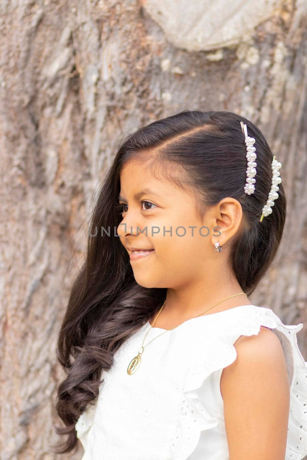 Little girl with white dress and red sweater, very happy and smiling in the forest