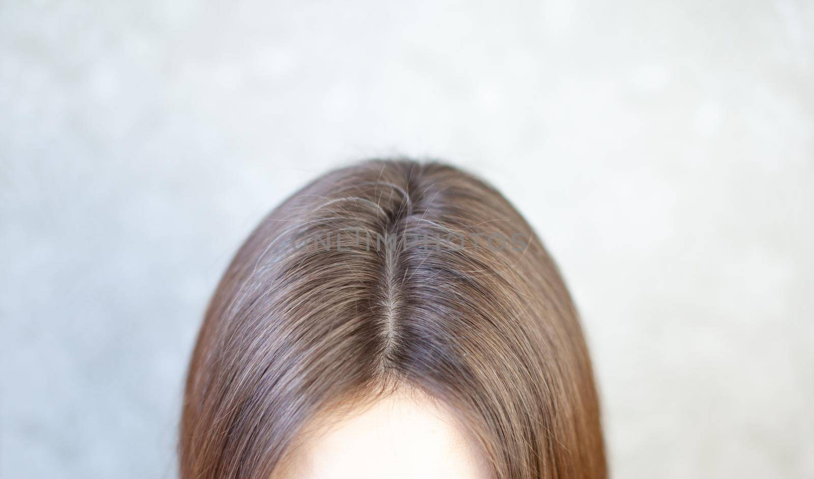 The head of a woman with a parting of gray hair. A woman does her hair. Brown hair on a woman's head close-up.