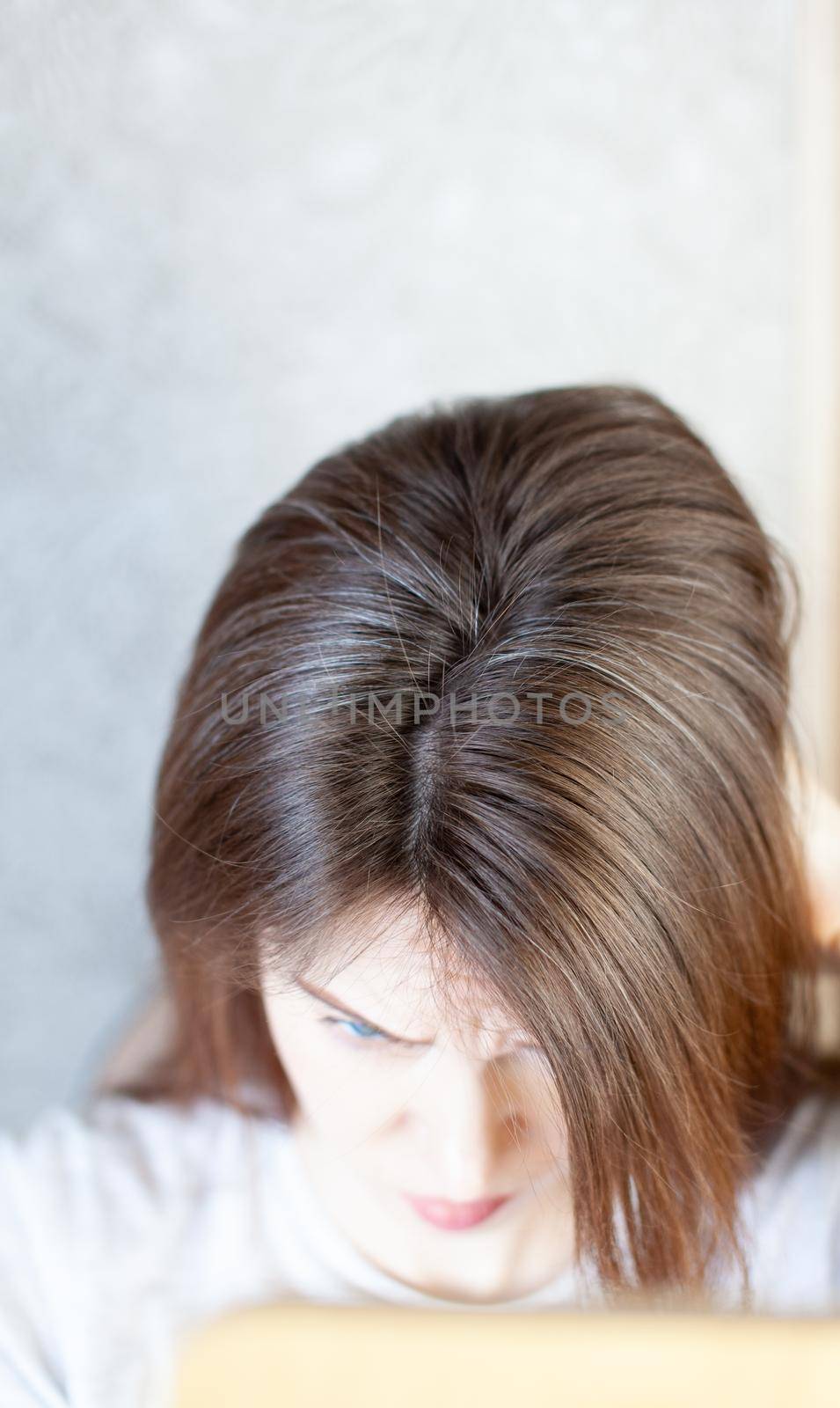 The head of a woman with a parting of gray hair. A woman does her hair. Brown hair on a woman's head close-up.