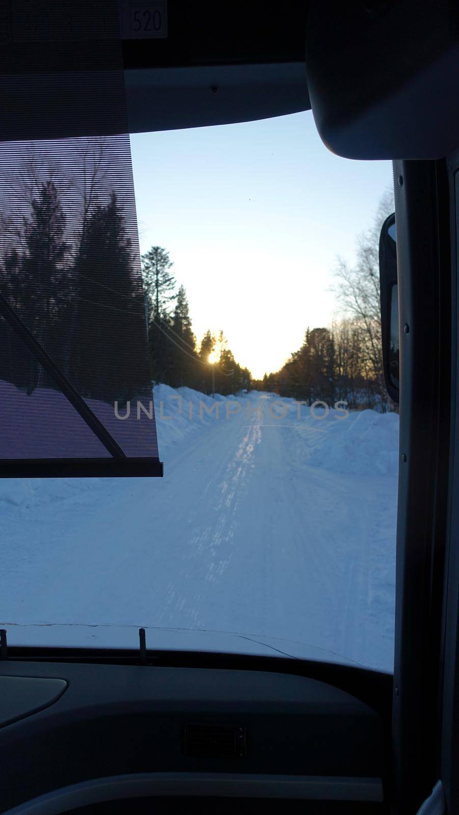 The snowy road in Northern Sweden seen during sunset from the bus