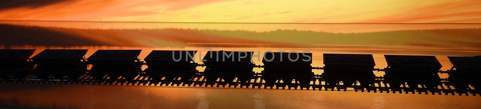 the wagons of a freight train parading on the rails during sunset by Jamaladeen
