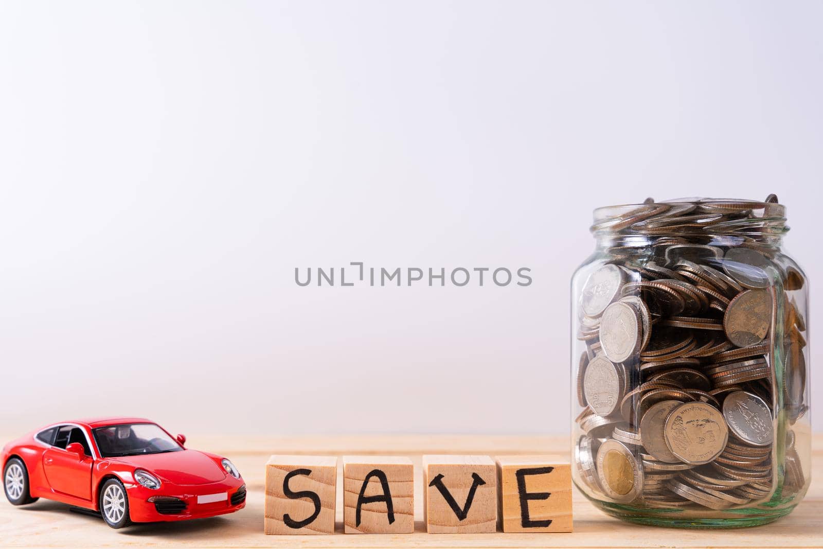 Wooden block stack with save word and jar full of coins and red car isolated grey background. Saving money and investment concept. by mikesaran
