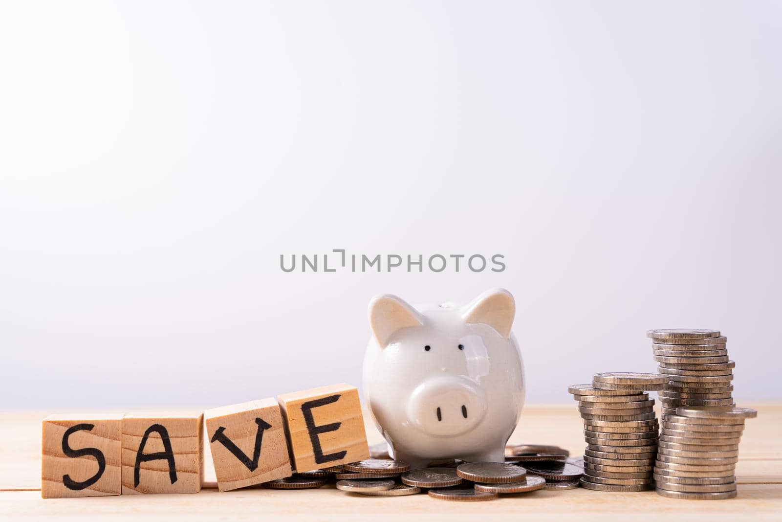 Piggy bank on stack coin and wood block with save word on wooden table isolated grey background. Saving money and investment concept.