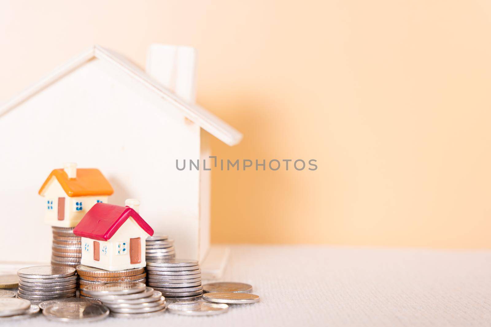 House on stack coins isolated orange background. Saving money and investment concept. by mikesaran