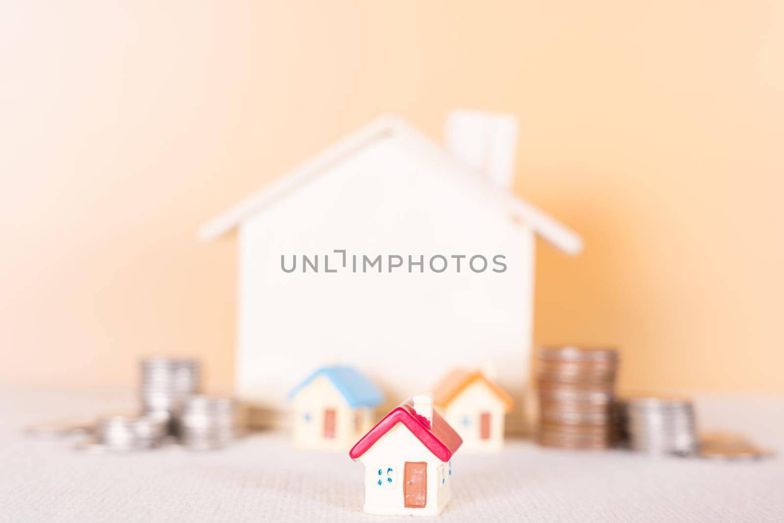 House and stack coins isolated orange background. Saving money and investment concept. by mikesaran