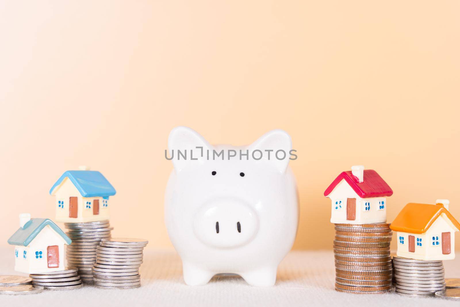 Piggy bank and house on stack coins isolated orange background. Saving money and investment concept.