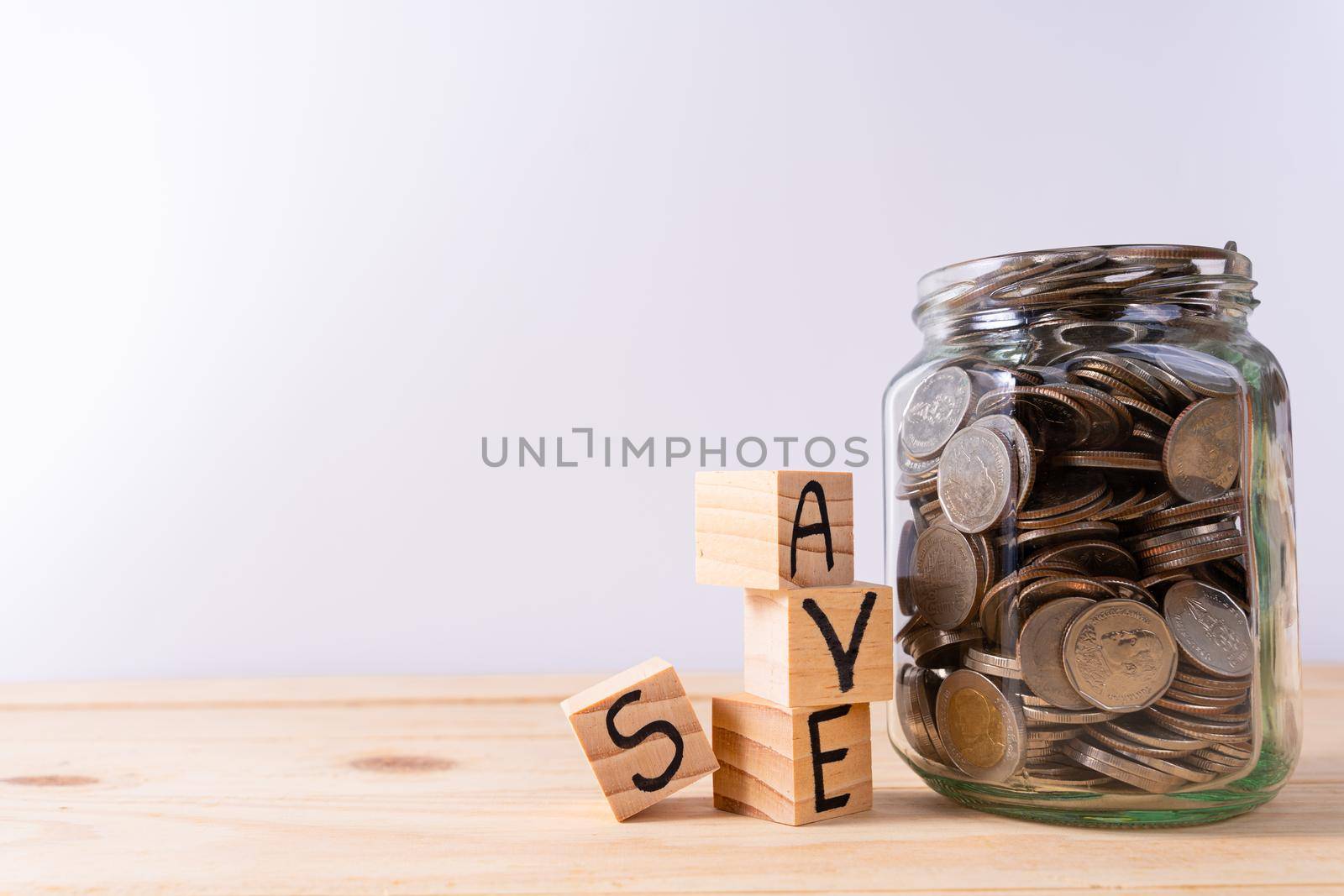 Wooden block stack with save word and jar full of coins isolated grey background. Saving money and investment concept. by mikesaran