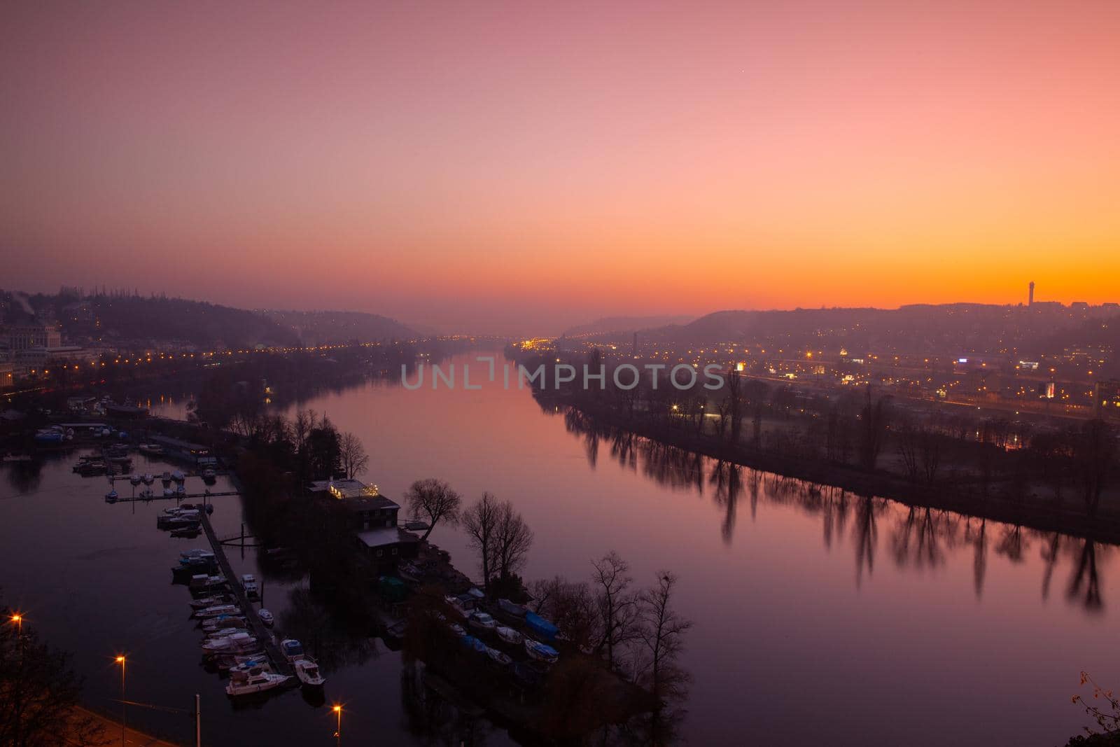 Small dock, boats and Vltava River in Prague, Czech Republic, viewed from the Vysehrad fort in the dramatic sunset.