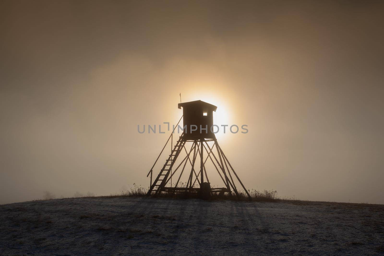 Lookout tower for hunting on the hill at sunrise. Winter scenery.