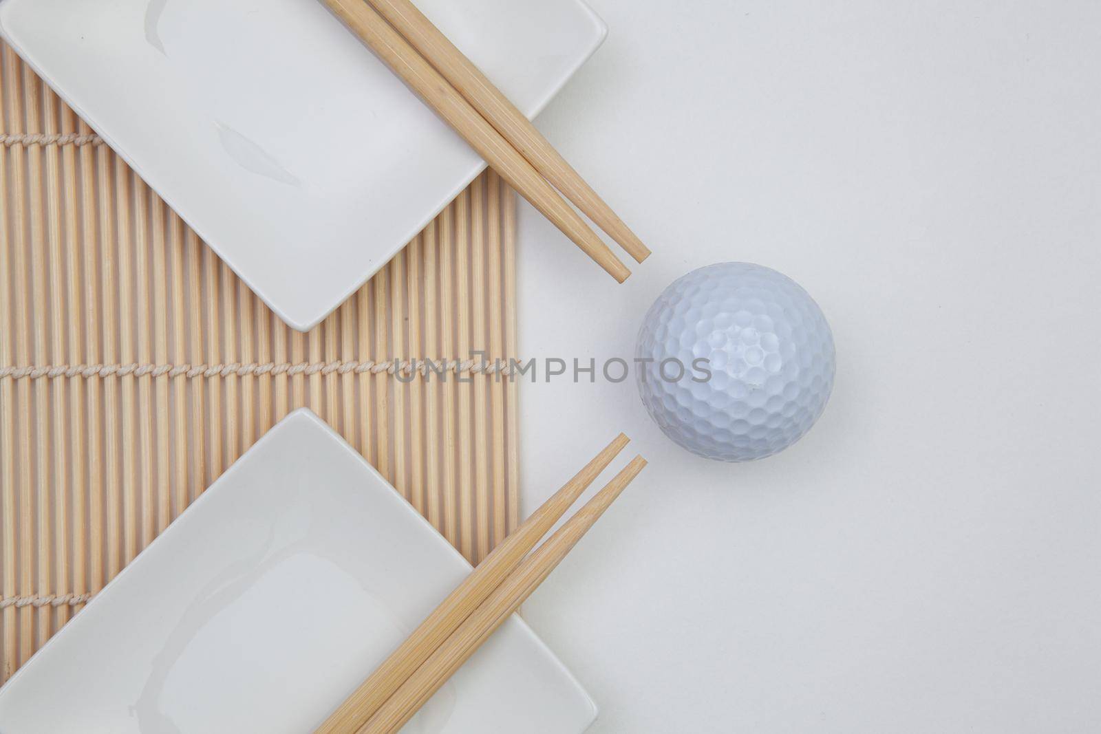 Top View Of White Empty Sushi Plates With Bamboo Chopsticks and Golf Ball.  by CaptureLight