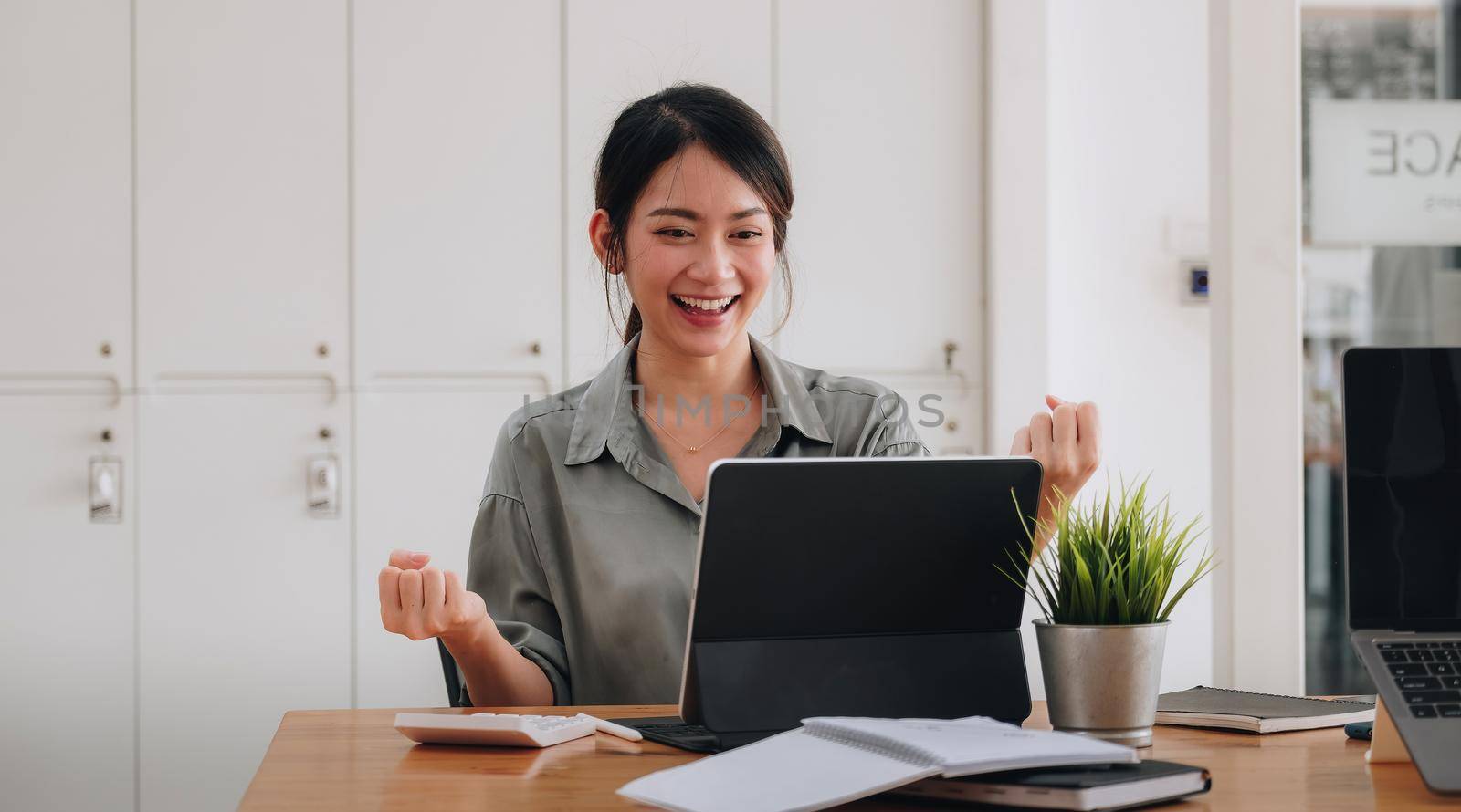 Portrait of an excited young asian girl using laptop computer and celebrating success for online learning or working at home by nateemee