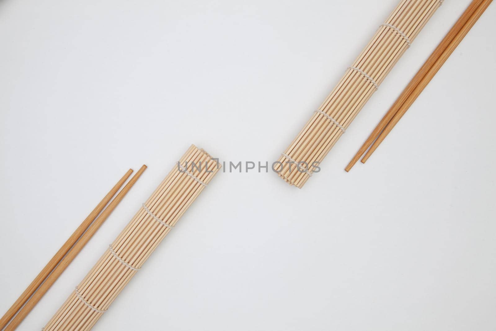 Bamboo mat with chopsticks for sushi on the white table.  by CaptureLight