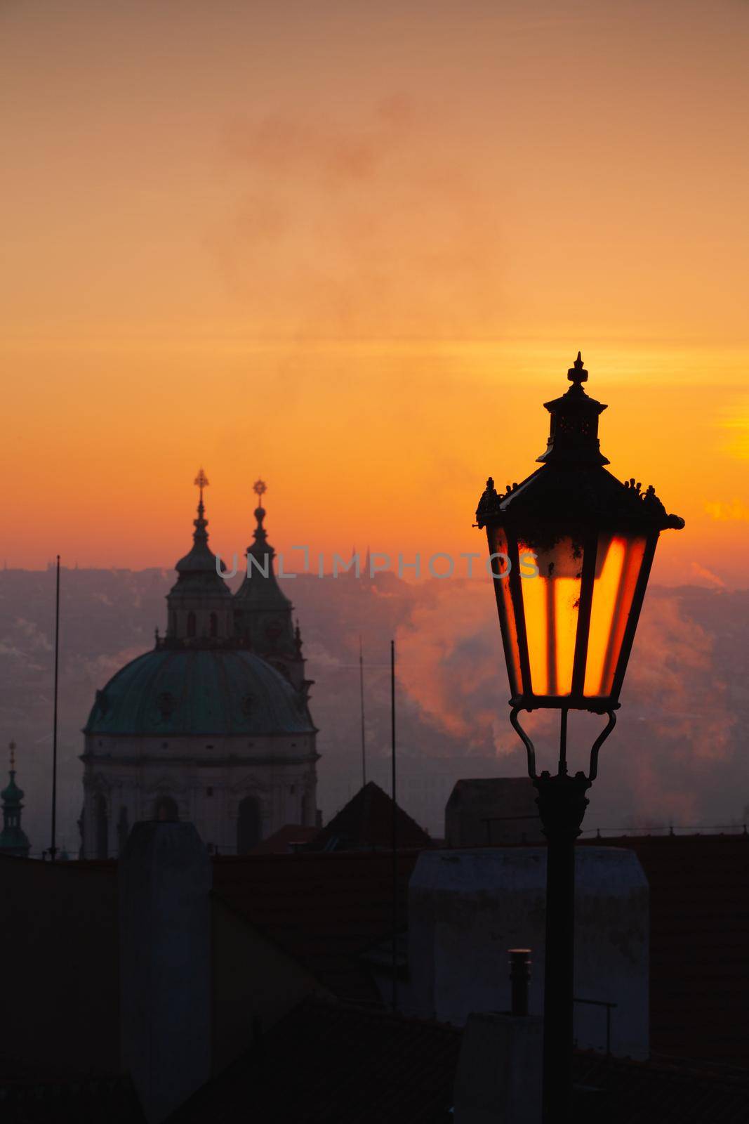 Sunrise behind an old street lamp over Lesser Town, Prague, Czech Republic. Lesser Town is a hillside area with views across the Vltava river to the old town.