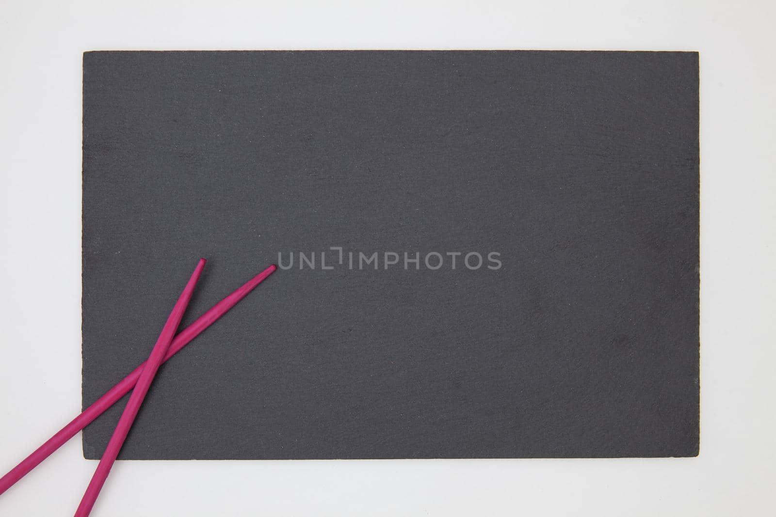 Rectangular slate plate with purple chopsticks for sushi on the white table. Food Design.
