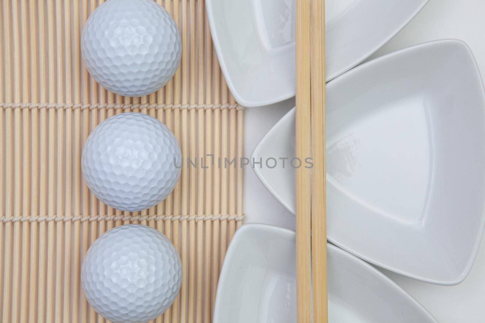 Top View Of White Empty Sushi Plates With Bamboo Chopsticks and Golf Balls.  by CaptureLight