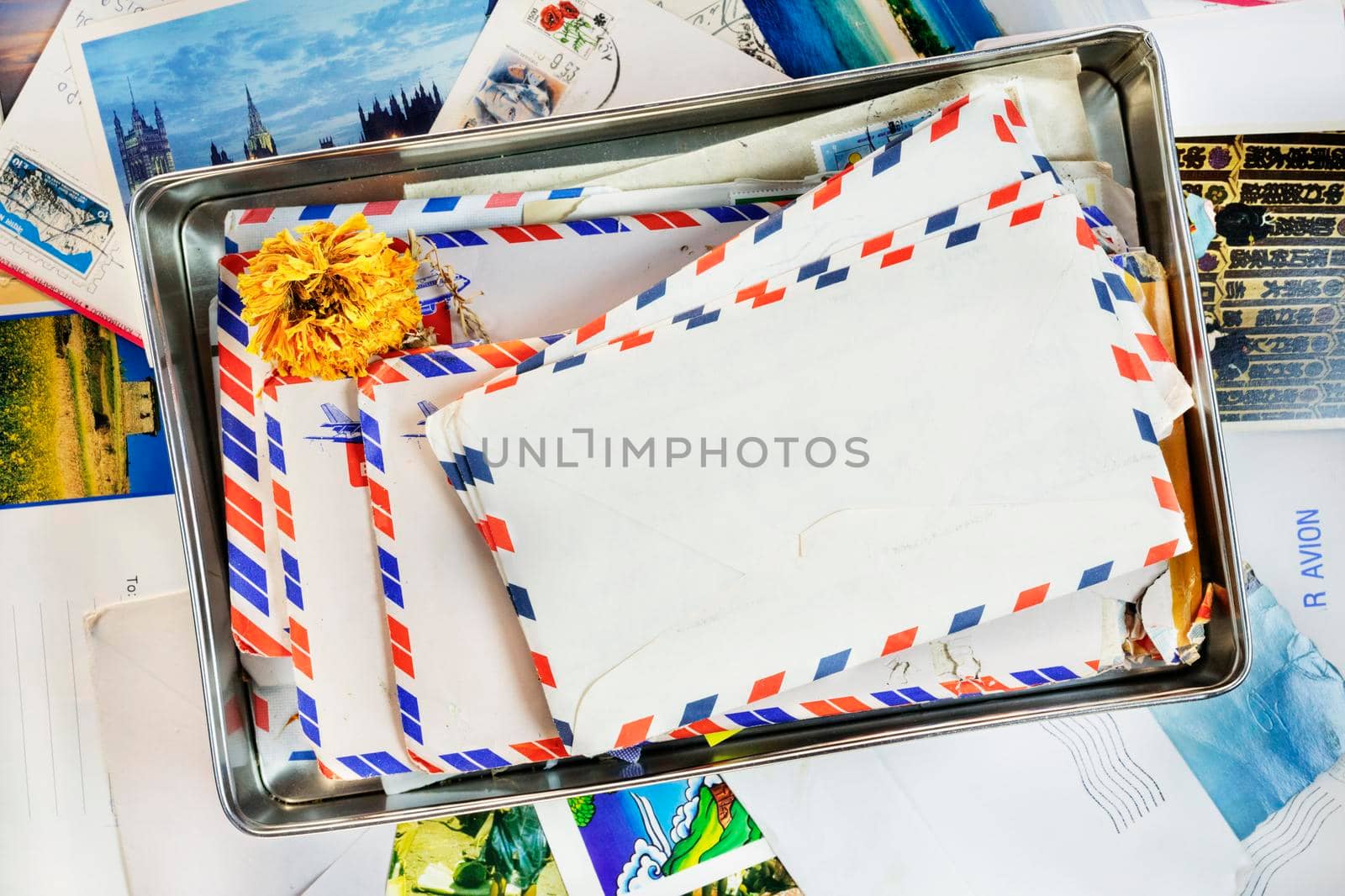 Old letters in a tin box with an orange dried flower , in the background postcards and letters