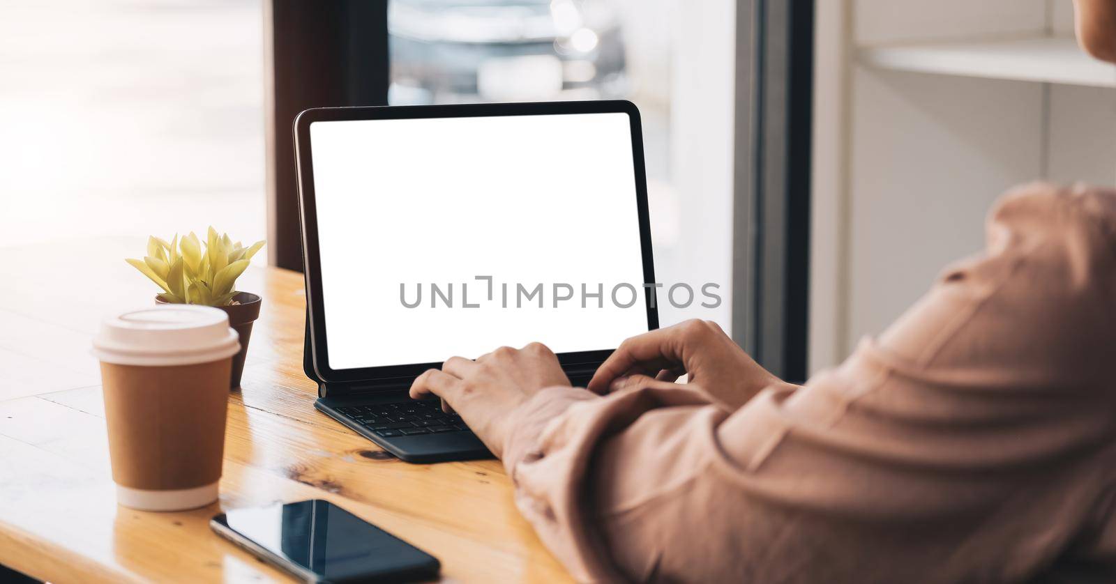 Cropped shot of young professional businesswoman typing on blank screen tablet and office supplies in simple workspace. by nateemee