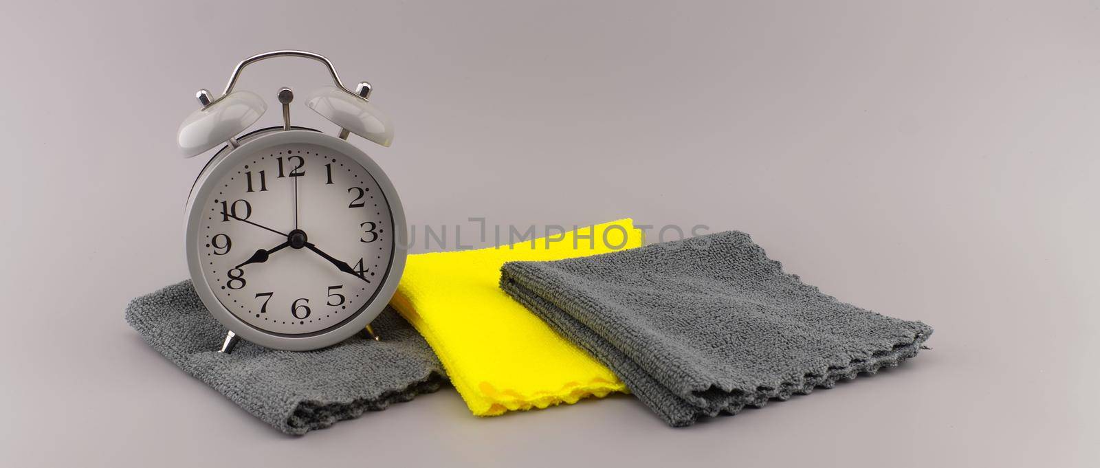 Color trends themed still life with alarm clock placed near two tone grey and yellow textile