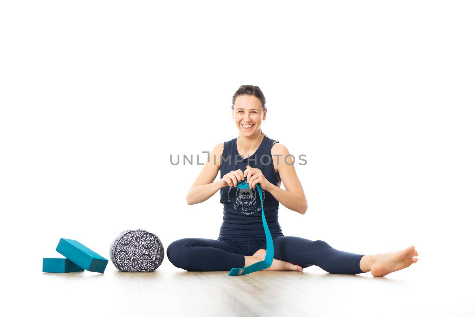 Restorative yoga with a bolster. Young sporty female yoga instructor in bright white yoga studio, smiling cheerfully while preparing restorative yoga exercise props by kasto