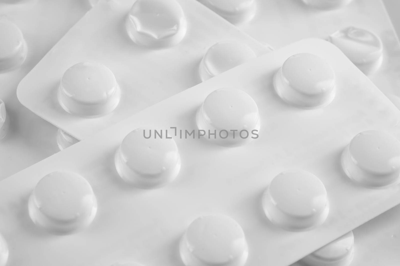 White pills in white blister on white background by Fischeron