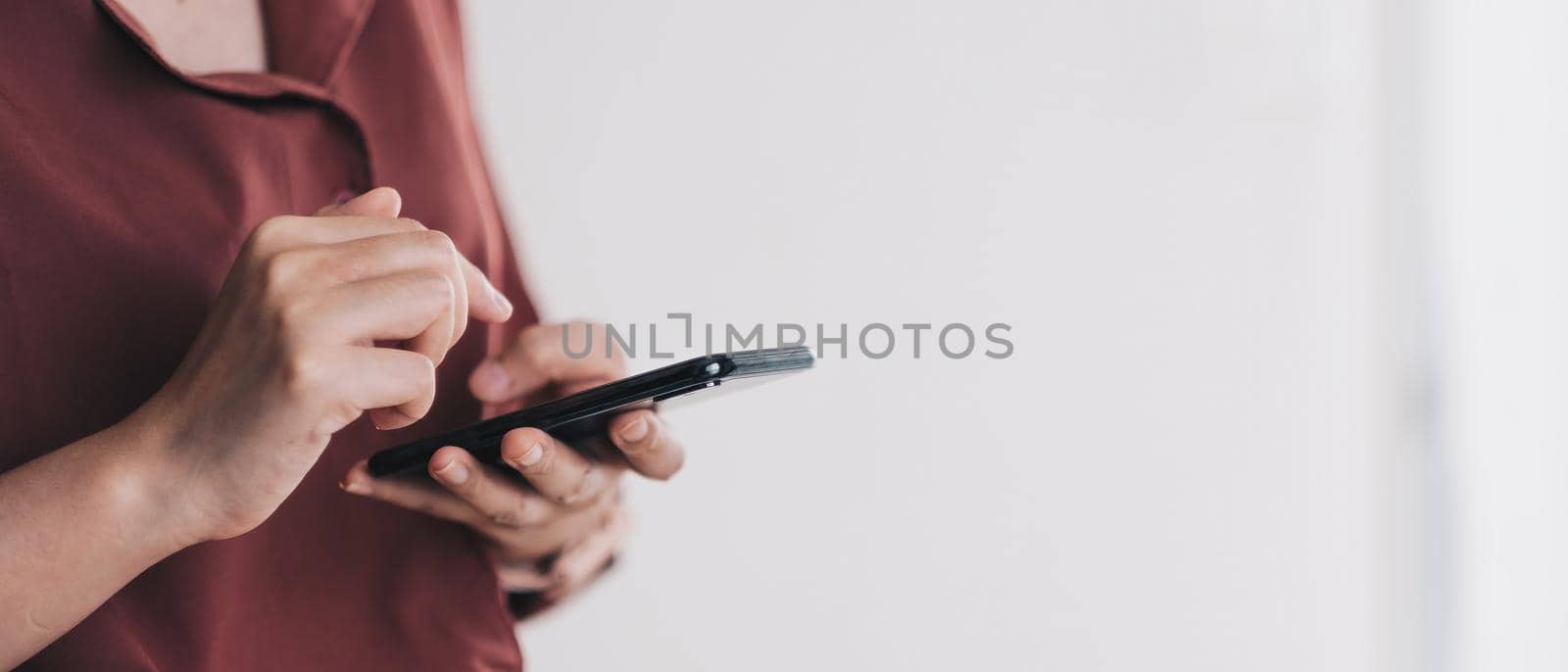 Women's hands use a smartphone for online shopping, social networking, or remote work. Close up image.