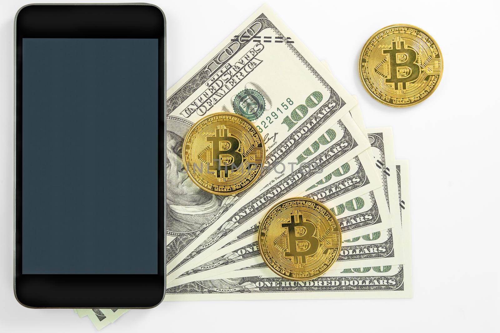 Bitcoins coin and  US banknotes of one hundred dollars with smartphone mockup. Close up of metal shiny bitcoin crypto currency coins and US dollar