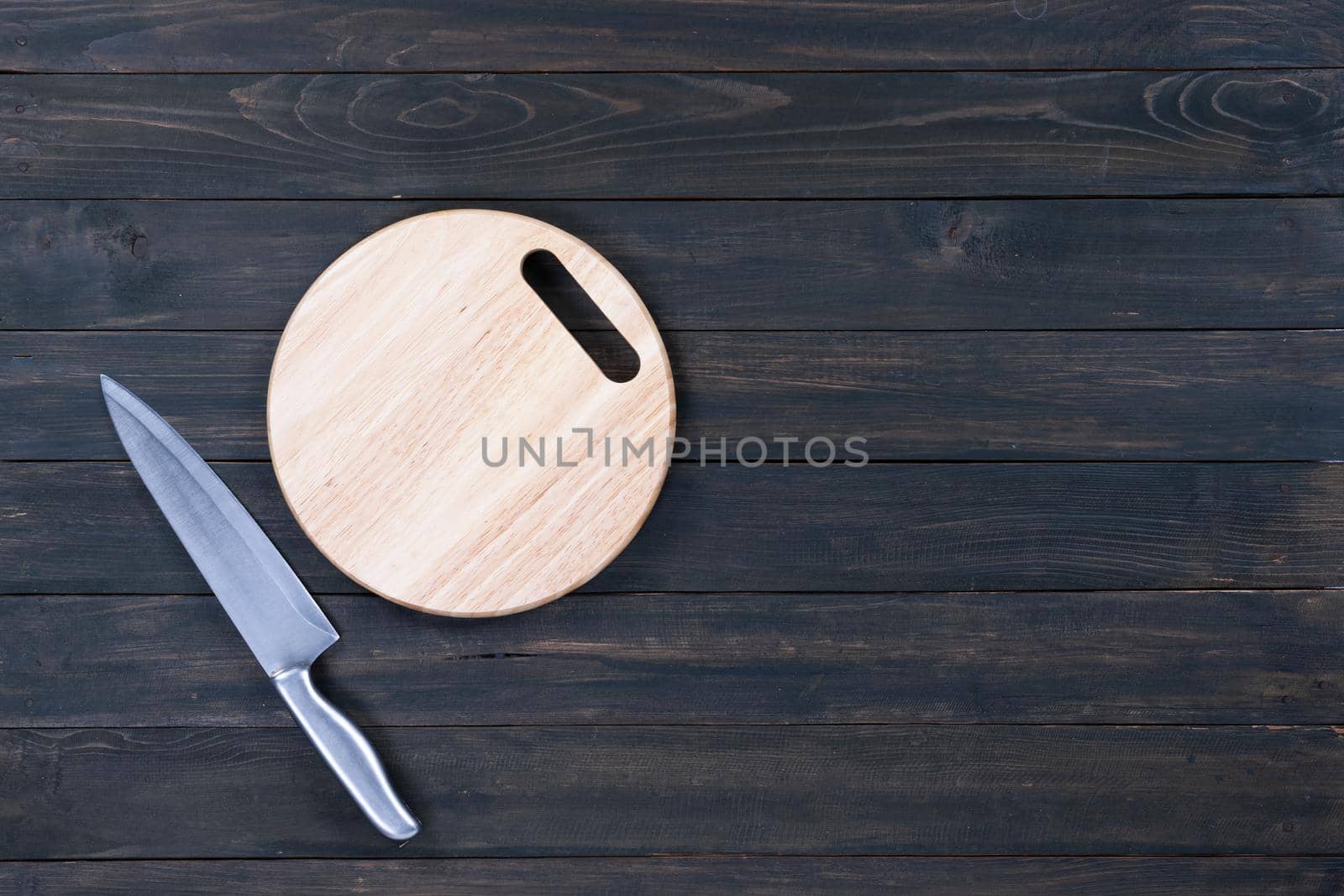 kitchen knife and wooden round empty cutting board on a wooden table close up