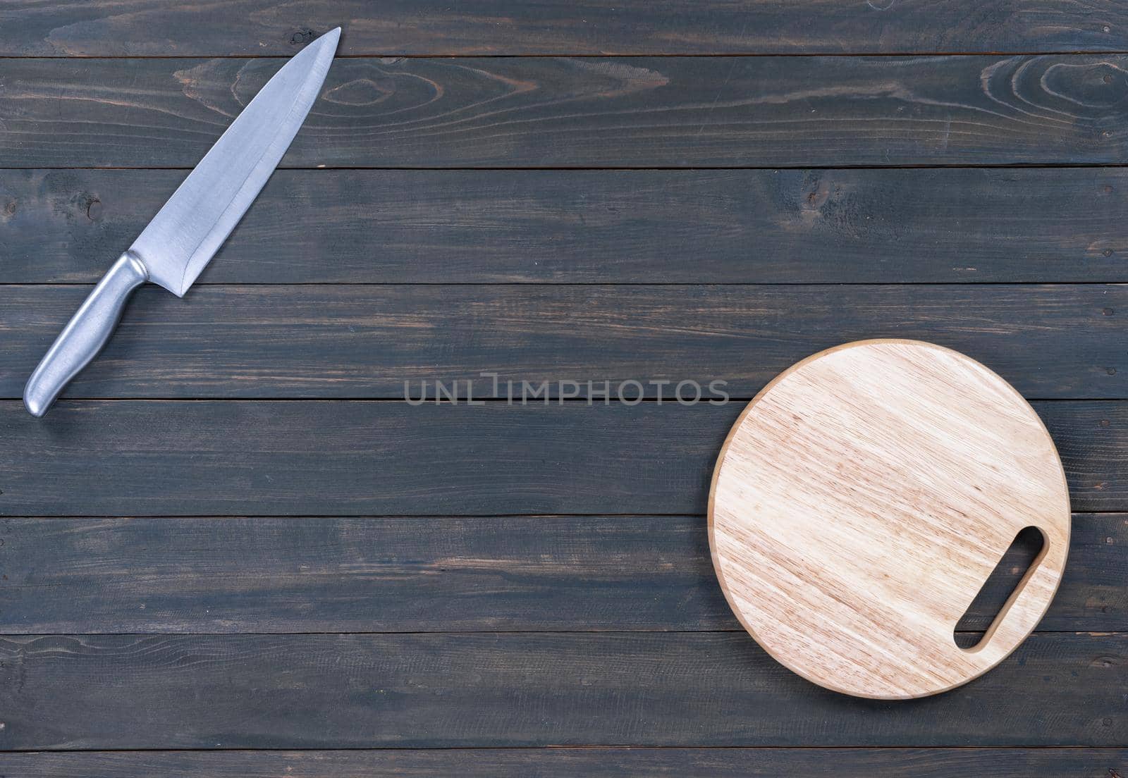 kitchen knife and wooden round empty cutting board on a wooden table close up