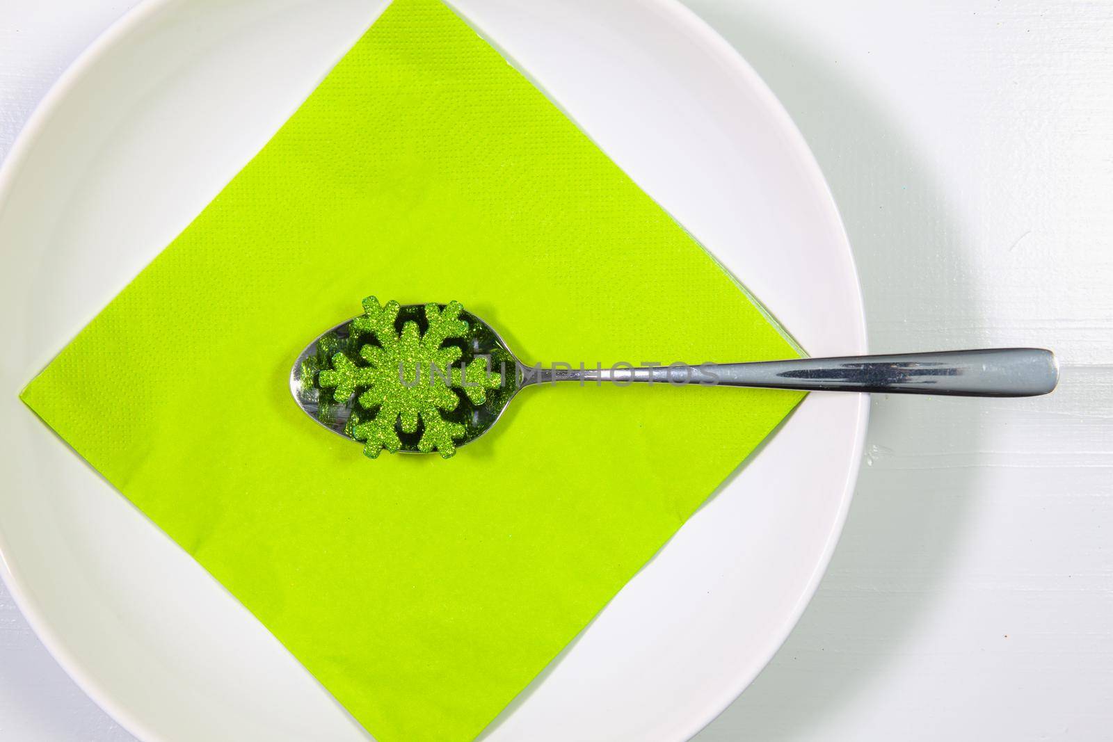 White plate and green Christmas decoration on the table. by CaptureLight