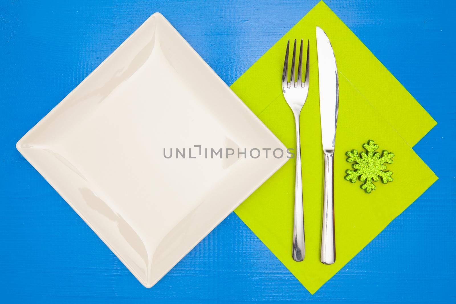 White square plate and green Christmas decoration on the blue wooden table.Top view.Flat Lay Image.