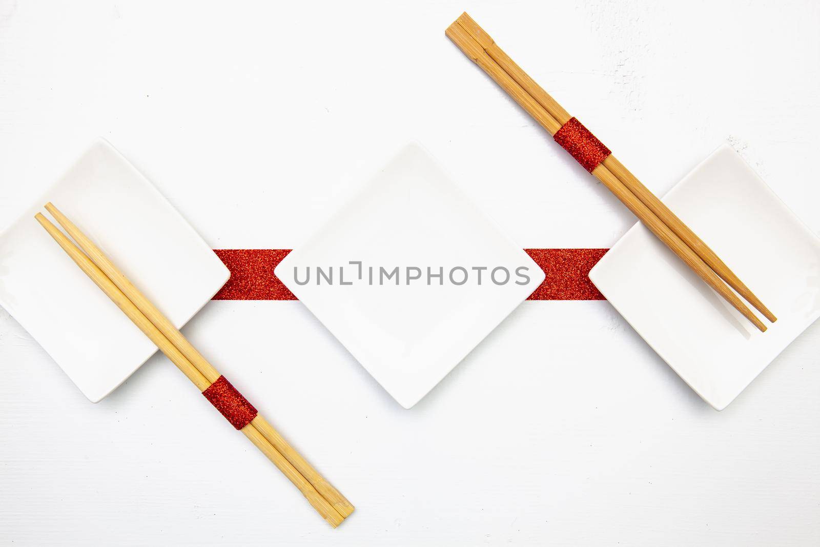 Ceramic bowls  and bamboo chopsticks for sushi food with red and white decoration.
