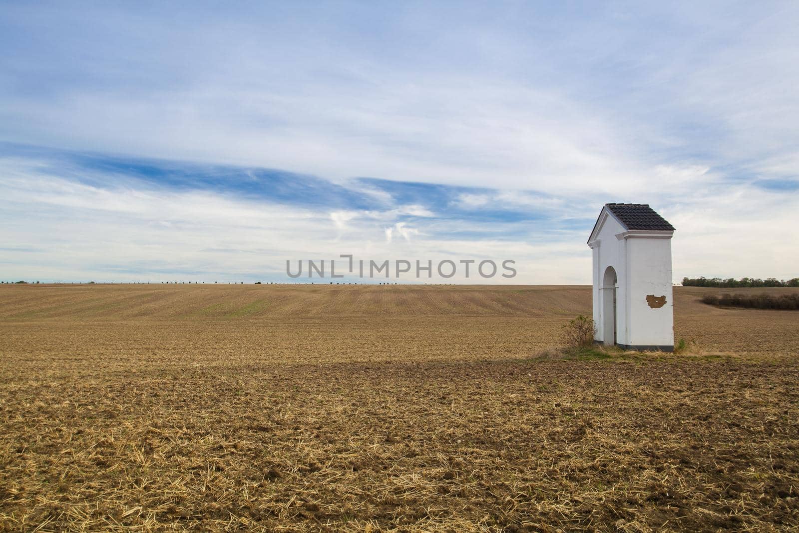 Small chapel in the autumn field. Autumn landscape with agricultural land, recently plowed and prepared for the crop.Central Bohemian Upland, Czech Republic.